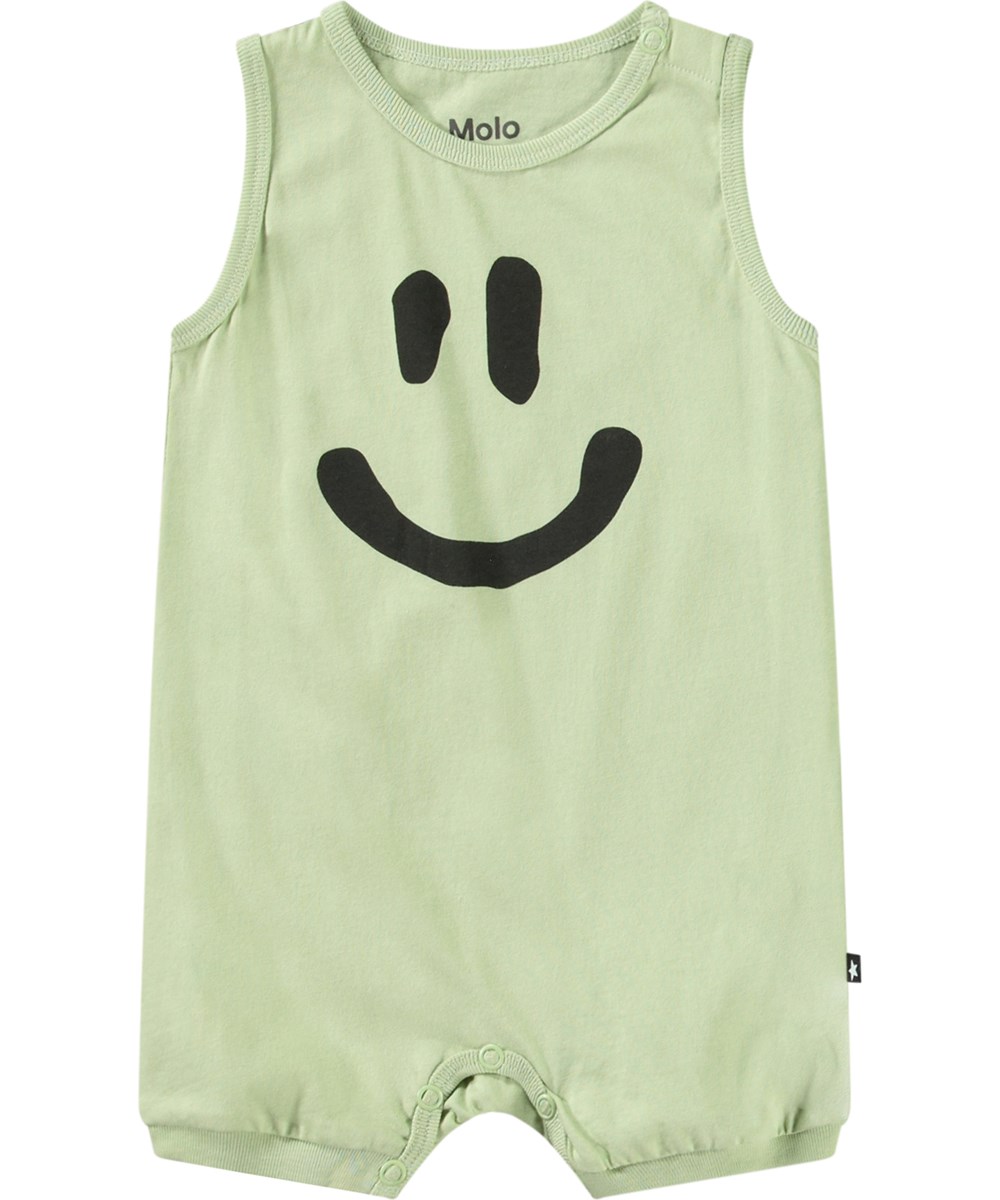 Fu - Misty Green - Jumpsuit aus weichem Öko-Baumwoll-Jersey. Ärmellos mit kurzen Beinen. Der Spielanzug ist hellgrün mit einem lächelnden Gesicht.