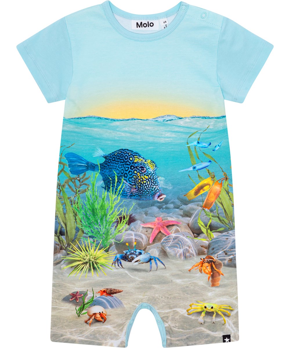 Finn - Tropic Sea Suit - Short sleeve, blue romper in organic cotton with print of a sunset and the bottom of the ocean with fish and plants
