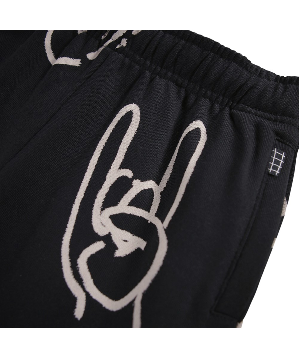 Adan - Drawn Hands - Zwarte joggingbroek voor kinderen gemaakt van biologisch katoen met een handtekeningenprint.