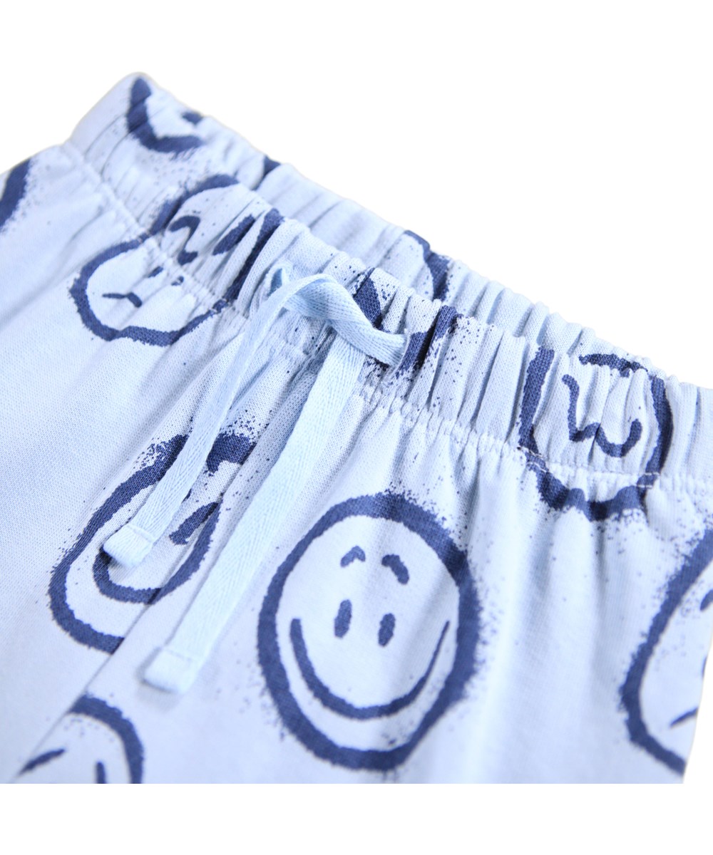 Simeon - Blue Moon Moods - Zachte lichtblauwe broek voor de kleintjes gemaakt van biologisch katoen met een print van blauwe gezichten in verschillende stemmingen.