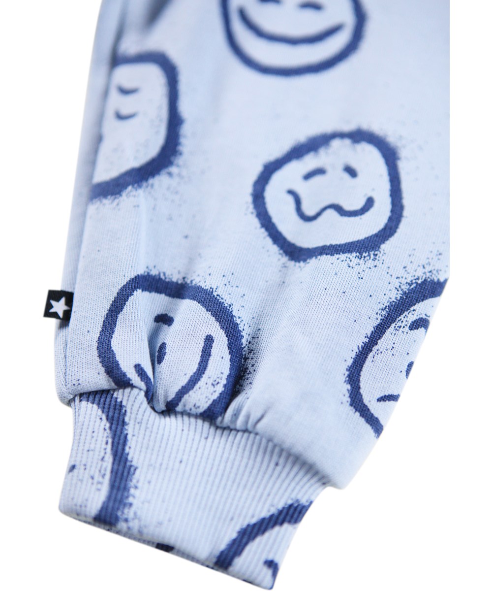 Simeon - Blue Moon Moods - Zachte lichtblauwe broek voor de kleintjes gemaakt van biologisch katoen met een print van blauwe gezichten in verschillende stemmingen.