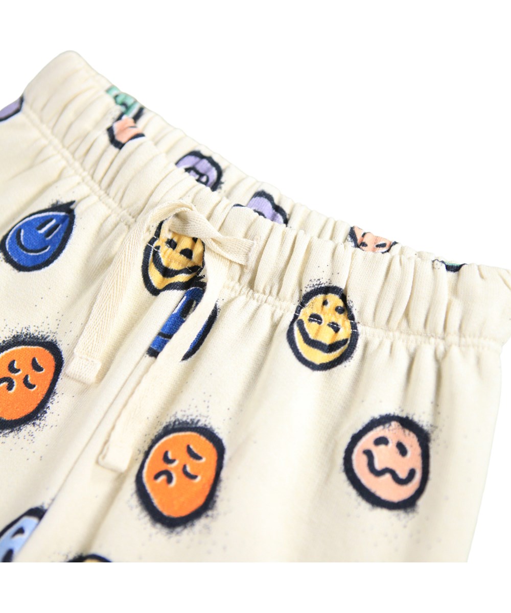 Simeon - Multi Moods - Zachte gebroken witte broek voor de kleintjes gemaakt van biologisch katoen met een print van kleurrijke gezichten in verschillende stemmingen.