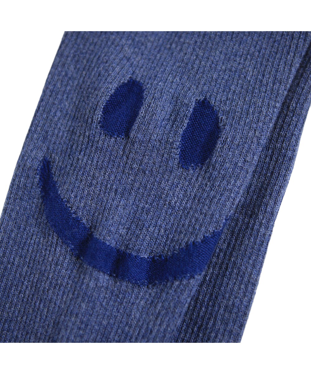 Stinus - Evening Sky - Blauwe gebreide broek voor de kleintjes gemaakt van zachte ribstof van katoen en wol met een lachend gezicht op het dijbeen.