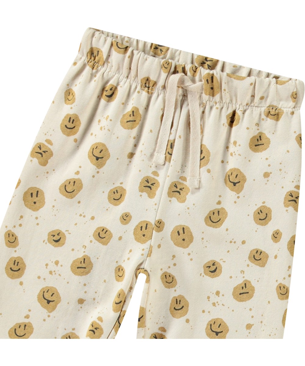 Simeon - Mood Dots - Bløde bukser i økologisk bomuld til baby. Bukserne er beige med smilende ansigter.