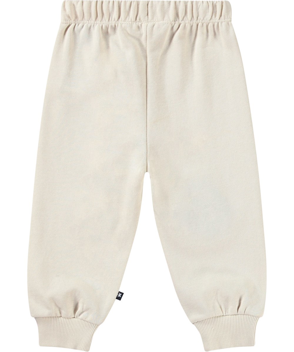 Simeon - Summer Sand - Bløde bukser i økologisk bomuld til baby. Bukserne er lys beige med bløde smilende ansigter.