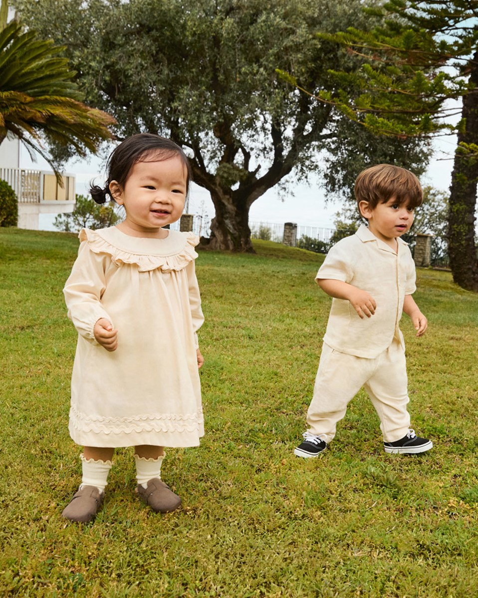 Eyou - Summer Sand - Kurzarmshirt aus Öko-Baumwolle für ein Baby. Das Shirt ist beige mit einem bestickten lächelnden Gesicht.