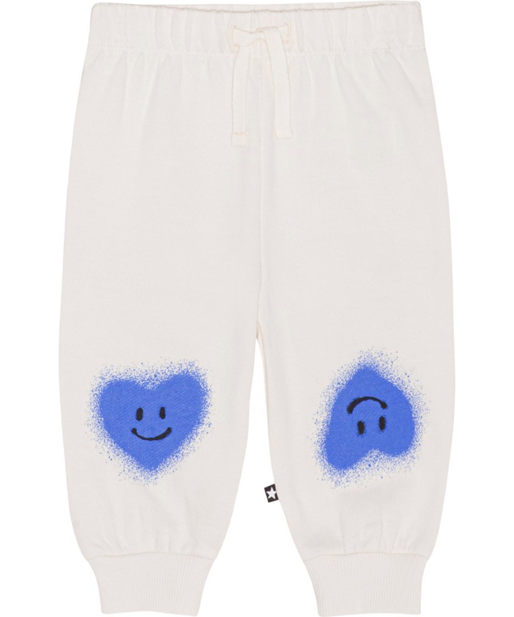 Simeon - Blue Heart - Cremefarbene Jogginghose aus Öko-Baumwolle mit einem Aufdruck aus blauen, lächelnden Herzen auf den Knien