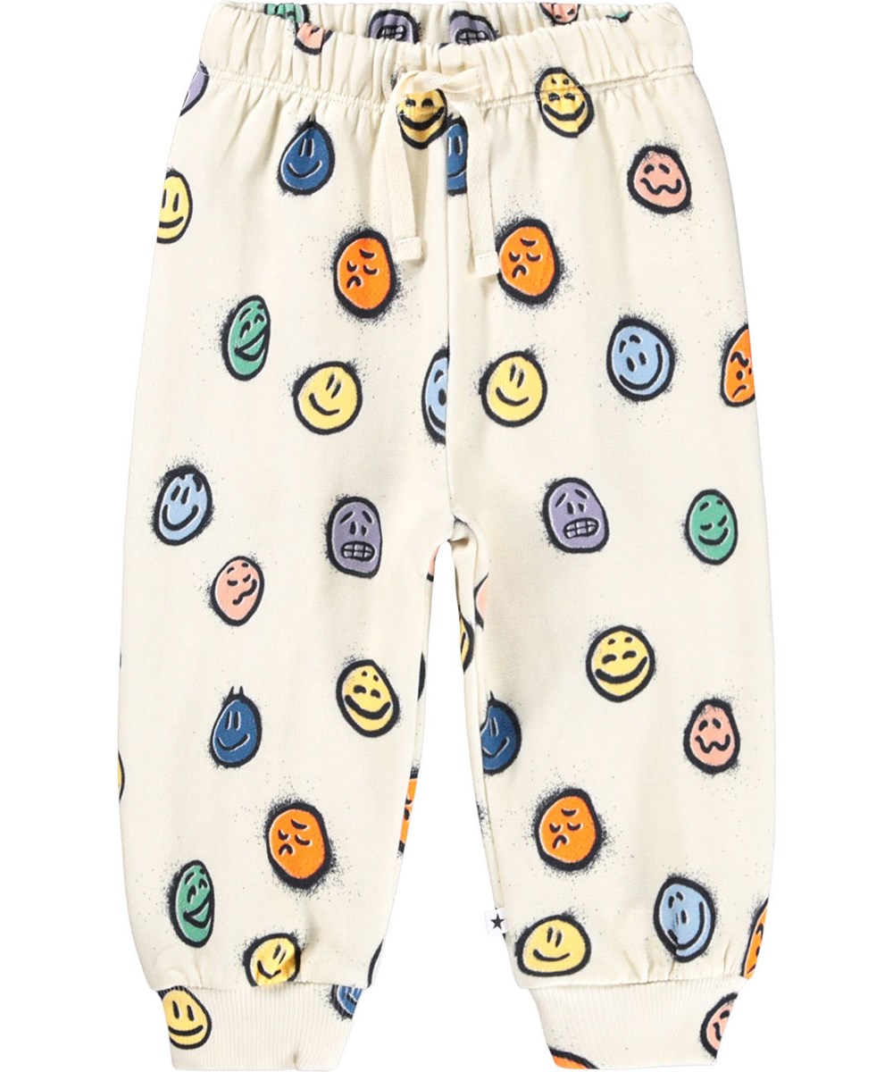 Simeon - Multi Moods - Weiche cremefarbene Hosen für die Kleinen aus Öko-Baumwolle mit einem Druck von bunten Gesichtern in verschiedenen Stimmungen.