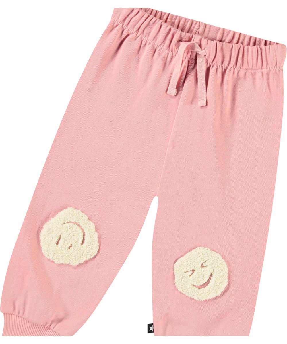Simeon - Rosequartz - Weiche Hosen aus Öko-Baumwolle für Babys. Die Hosen sind in Pink mit sanften lächelnden Gesichtern.