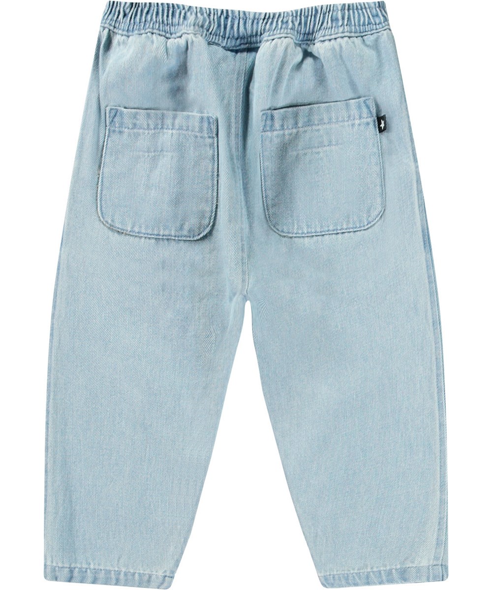 Sois - Misty Denim - Hose aus Öko-Baumwolle für Babys. In blauem Denim mit einem lächelnden Gesicht bestickt neben der Tasche.