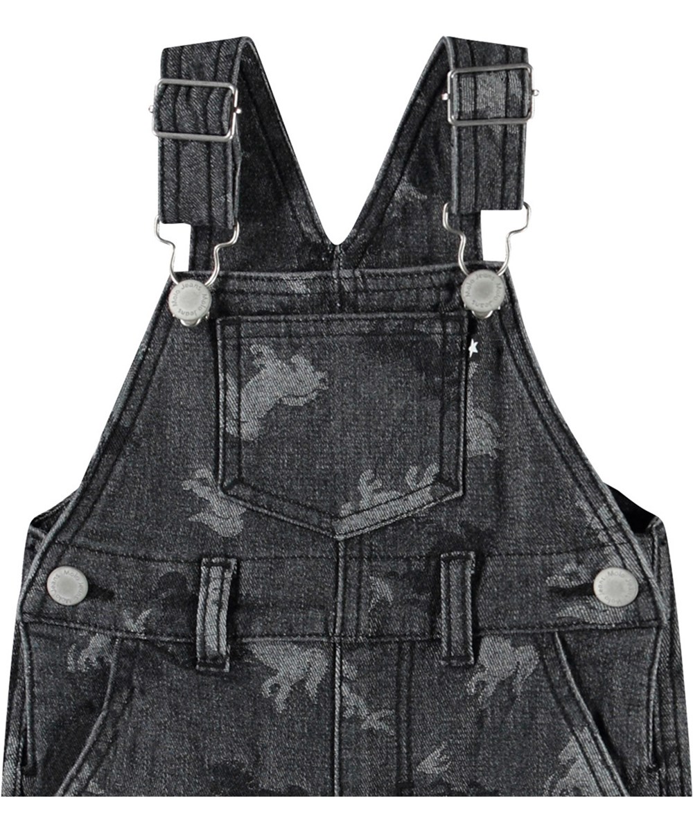 Spark - Giddy-Up Denim - Latzhosen aus Öko-Baumwolle für Babys. Die Latzhosen sind dunkelgrau mit Jacquard-gewebten Pferden.