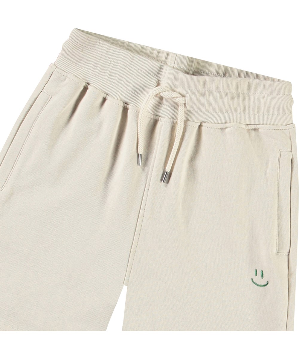 Alw - White Noise - Beige kindershort van biologisch katoen met een groene smiley.
