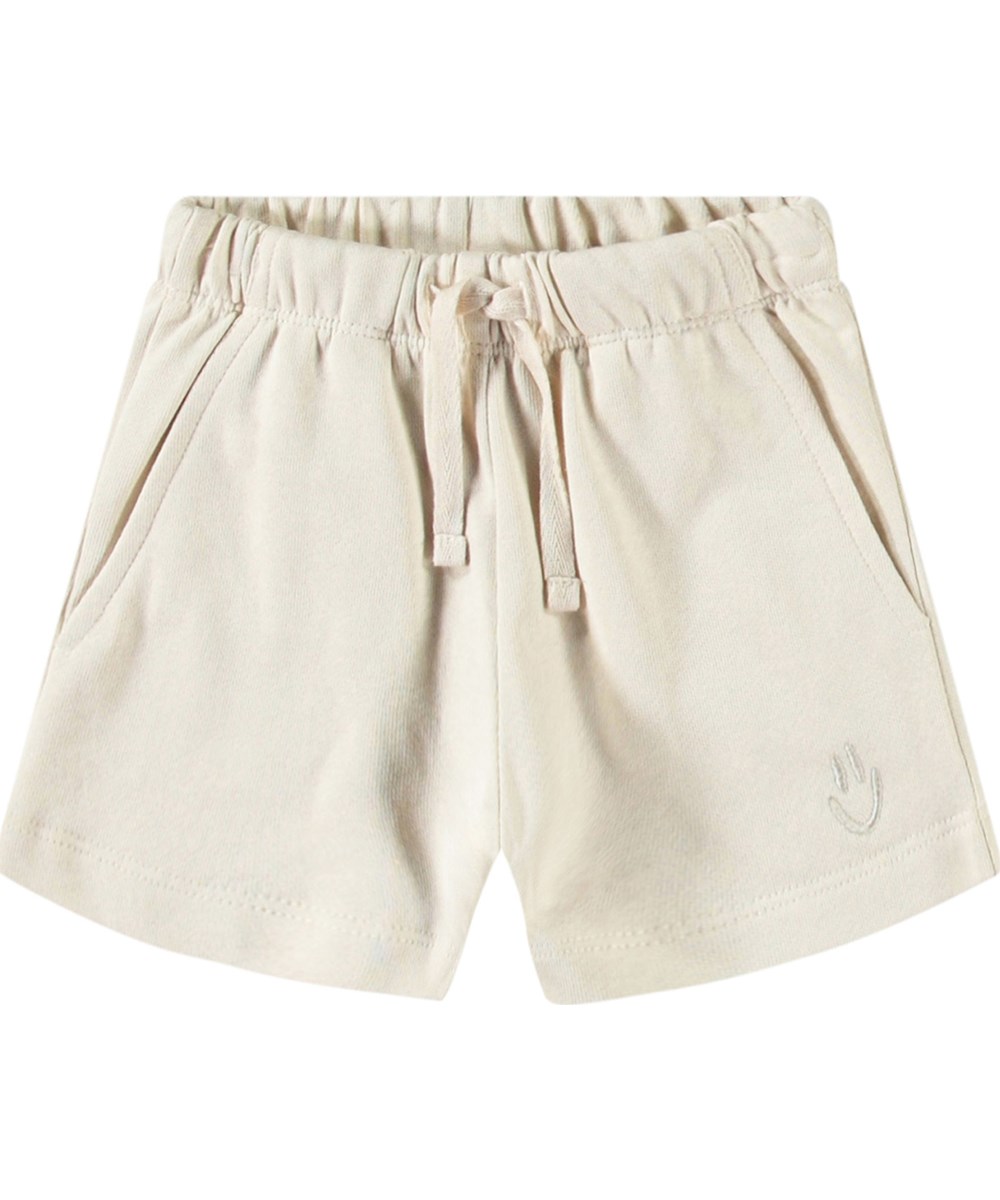 Simms - Summer Sand - Zachte babyshort van biologisch katoen. De short is lichtbeige met op een pijp een geborduurde smiley.