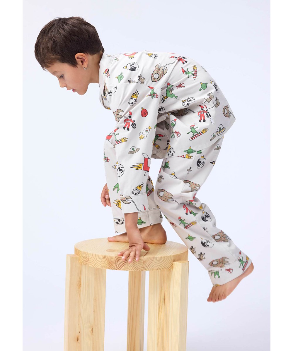 Lex - Spacy Nights - Beige kinderpyjama gemaakt van biologisch katoen met een kerst in de ruimte print.