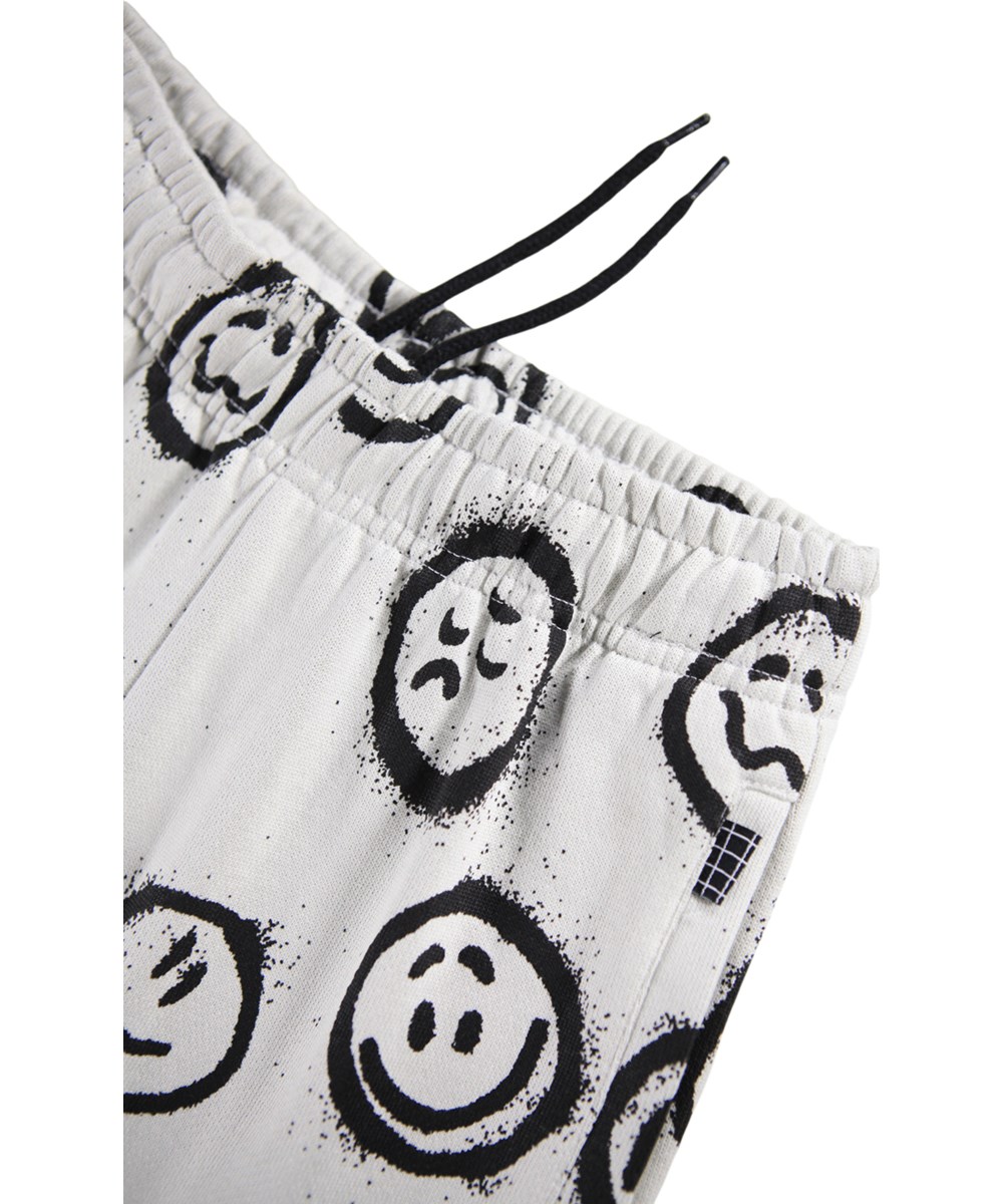 Adan - Different Moods - Off-white sweatpants for children made of organic cotton with a print of faces.