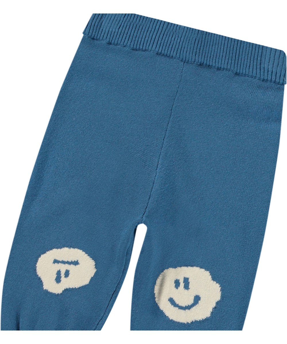 Sol - Lagoa - Knitted pants in organic cotton for baby. Knitted in blue with smiling faces decorated on the knees.