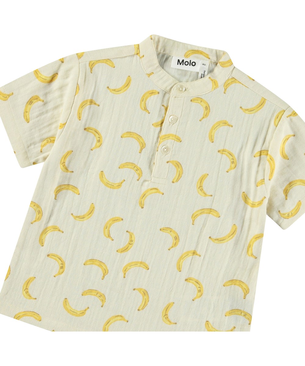 Ever - Cute Bananas - Kortærmet skjorte med knapper i økologisk crepet bomuld til baby. Skjorten er beige med print af bananer.