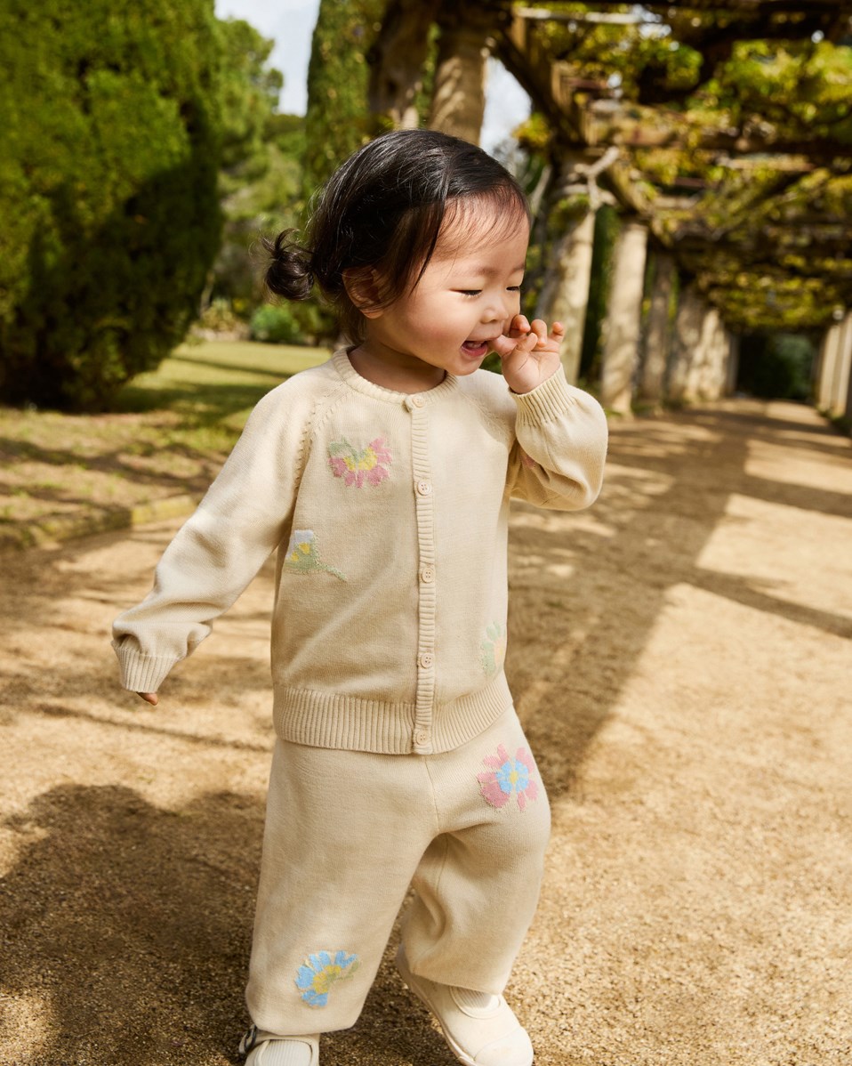 Brody - Pastel Flora - Knitted cardigan for baby in soft organic cotton. The cardigan is beige with flowers.