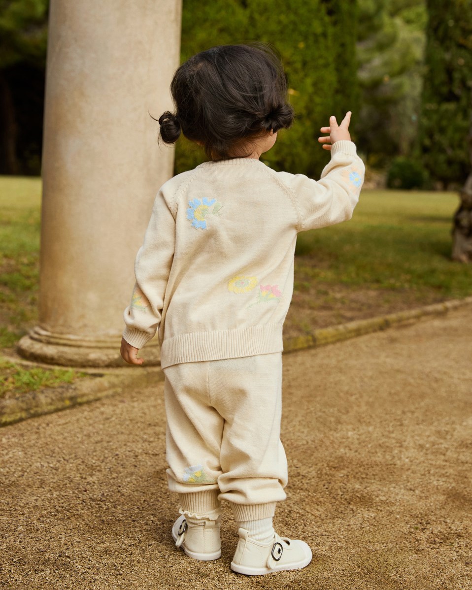 Brody - Pastel Flora - Knitted cardigan for baby in soft organic cotton. The cardigan is beige with flowers.