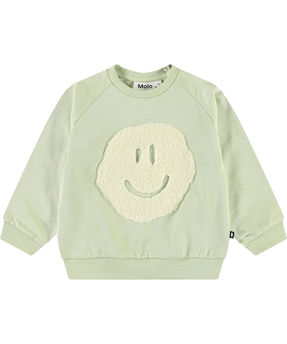 Disc - Misty Green - Organic light green baby sweatshirt with a soft smiling face.