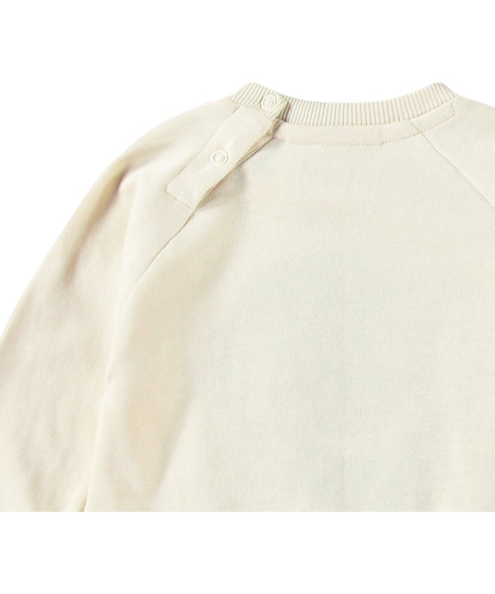 Disc - Summer Sand - Organic beige baby sweatshirt with a soft smiling face in blue.