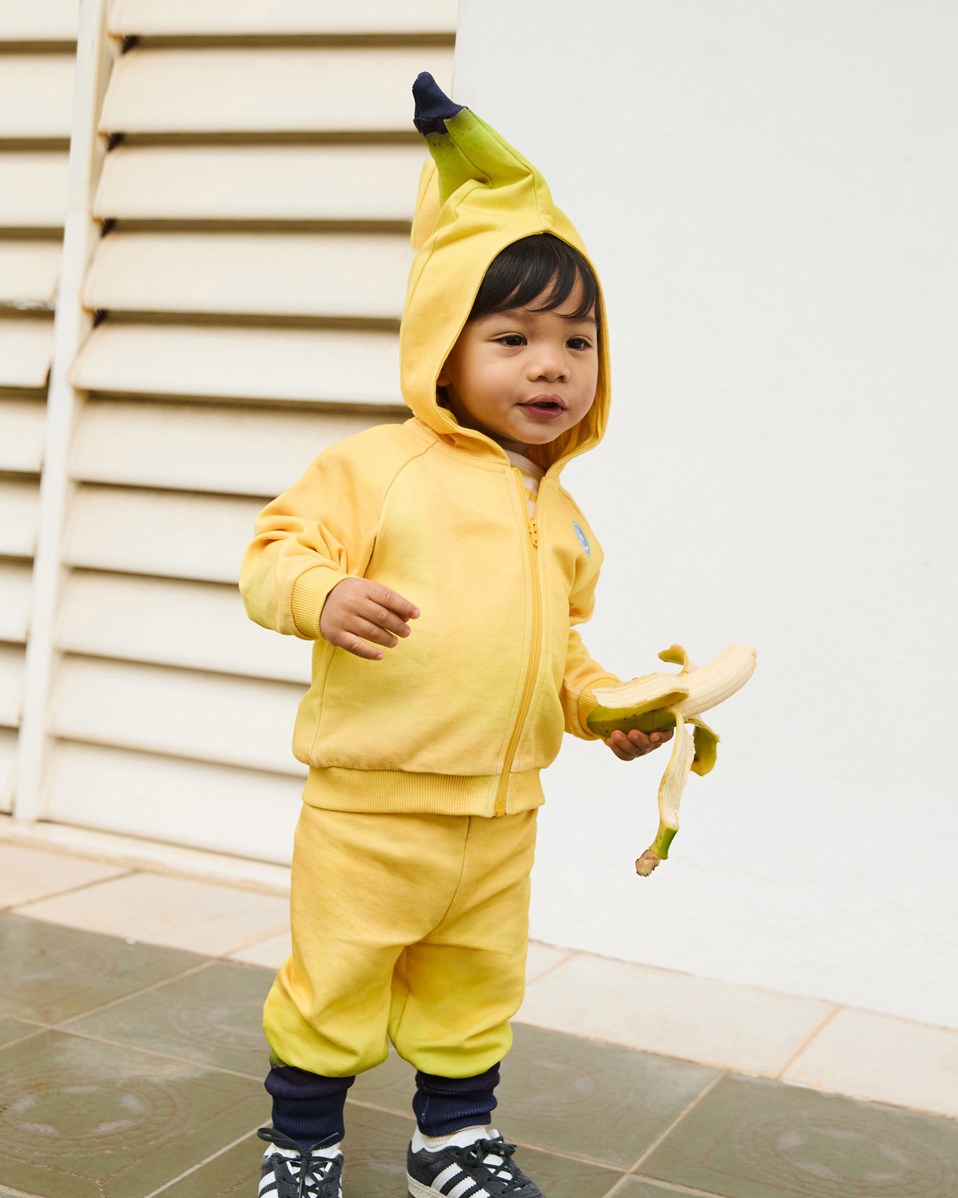 Dani -  Be A Banana - Kapuzenpullover aus Öko-Baumwolle für Babys. Der Kapuzenpullover ist gelb mit Bananen-Details.