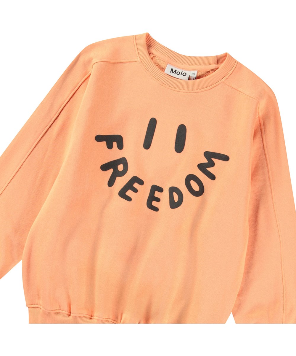 Mir - Cantaloupe - Oranger Pullover mit Druck für Kinder aus weicher Öko-Baumwolle mit gerippten Kanten am Hals, an den Ärmeln und am unteren Saum des Pullovers.