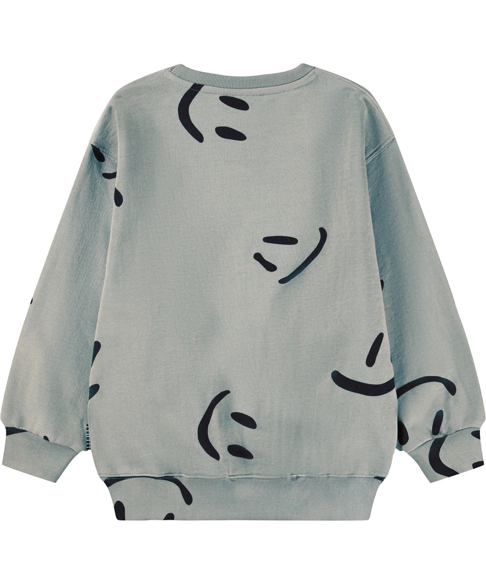 Monti - Big Smiles Fall - Beiges Sweatshirt für Kinder aus weicher Öko-Baumwolle mit einem Aufdruck von lächelnden Gesichtern.