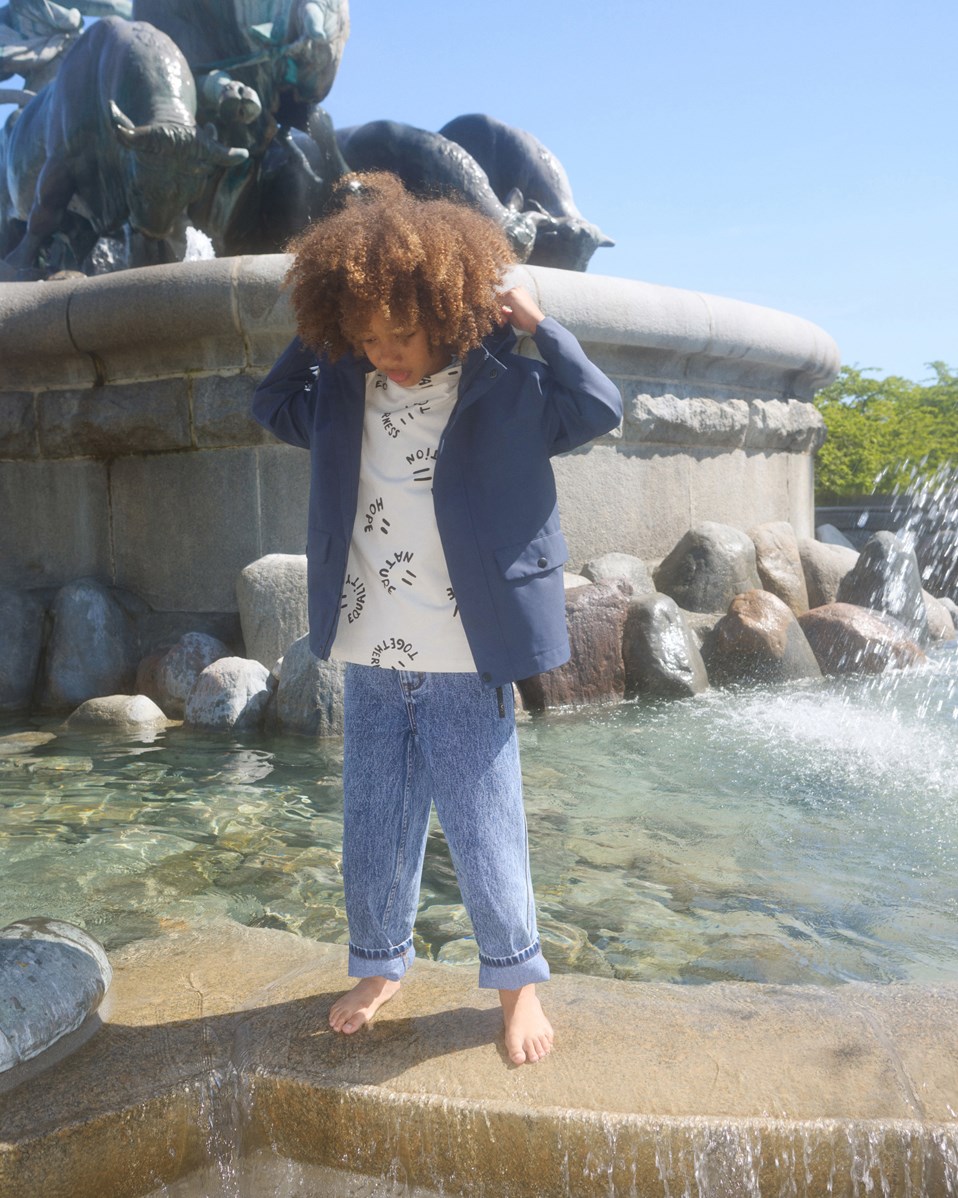 Riley - Smiling Words - Off-weißes T-Shirt mit Druck für Kinder aus weicher Öko-Baumwolle mit kurzen Ärmeln und geripptem Ausschnitt.