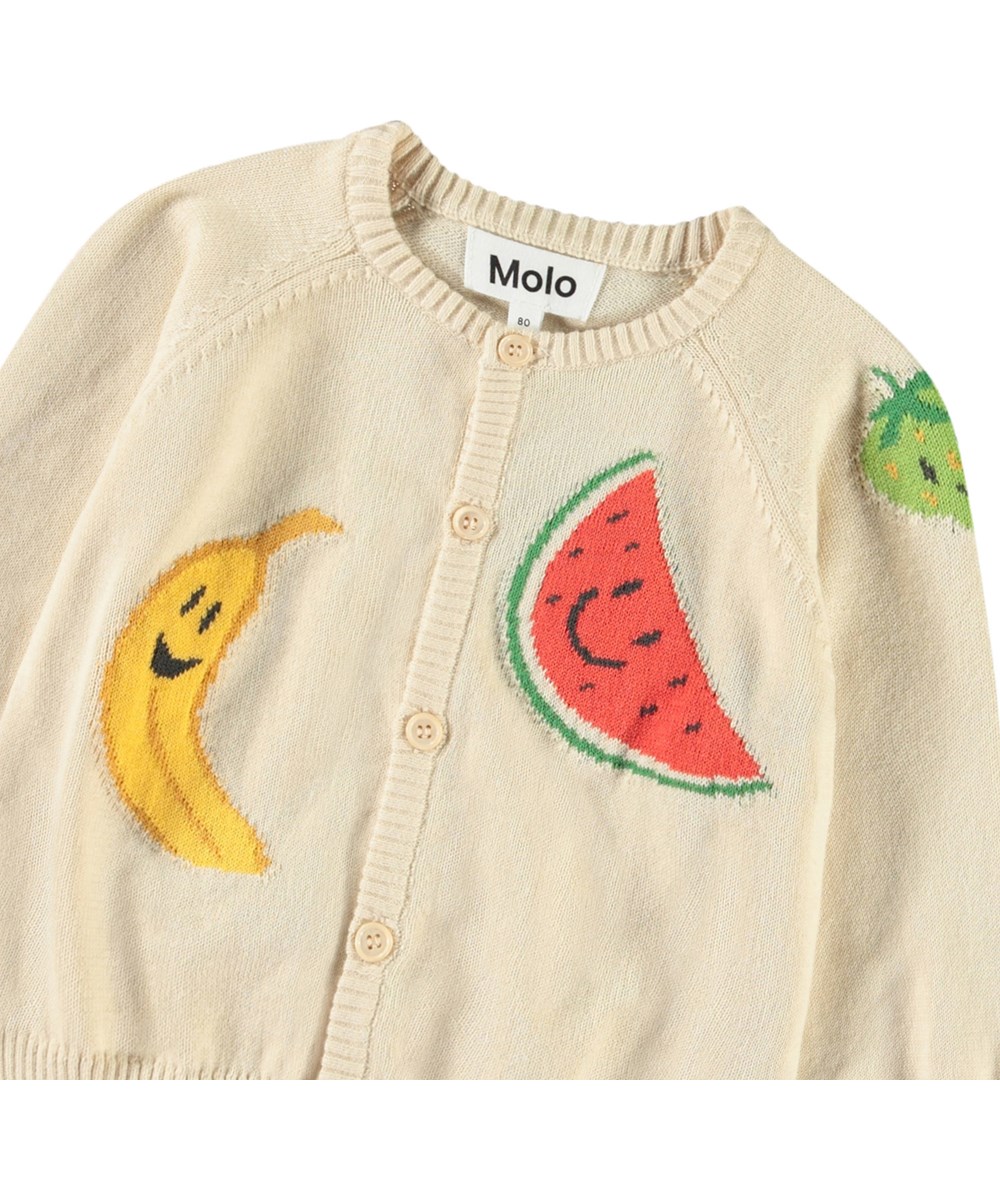 Brody - Cute Fruits - Strikcardigan til baby i blød økologisk bomuld. Cardiganen er beige med glade frugter på.