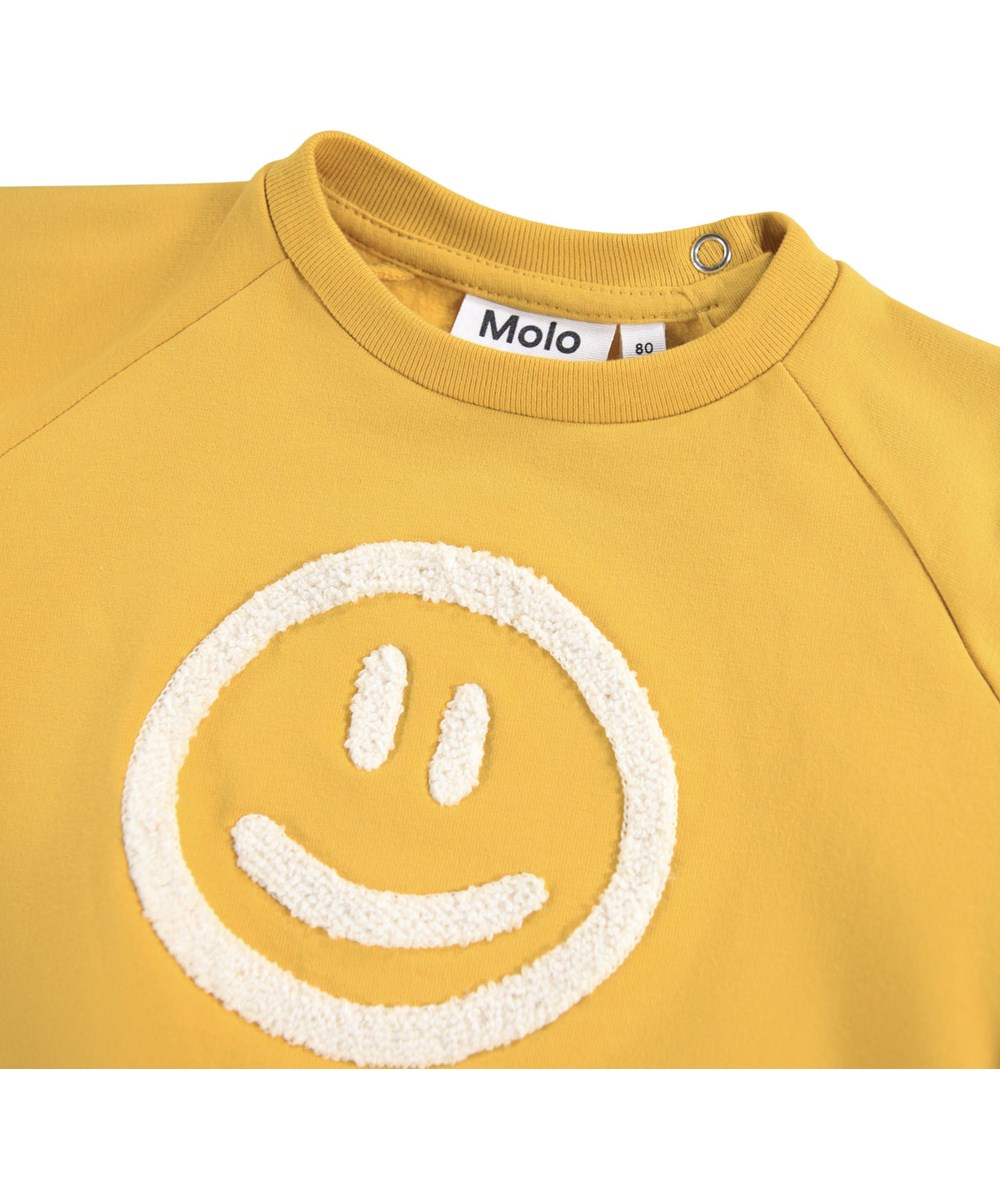 Disc - Energy - Gul sweatshirt til de mindste i blødt økologisk bomuld med et broderet smilende ansigt på fronten.