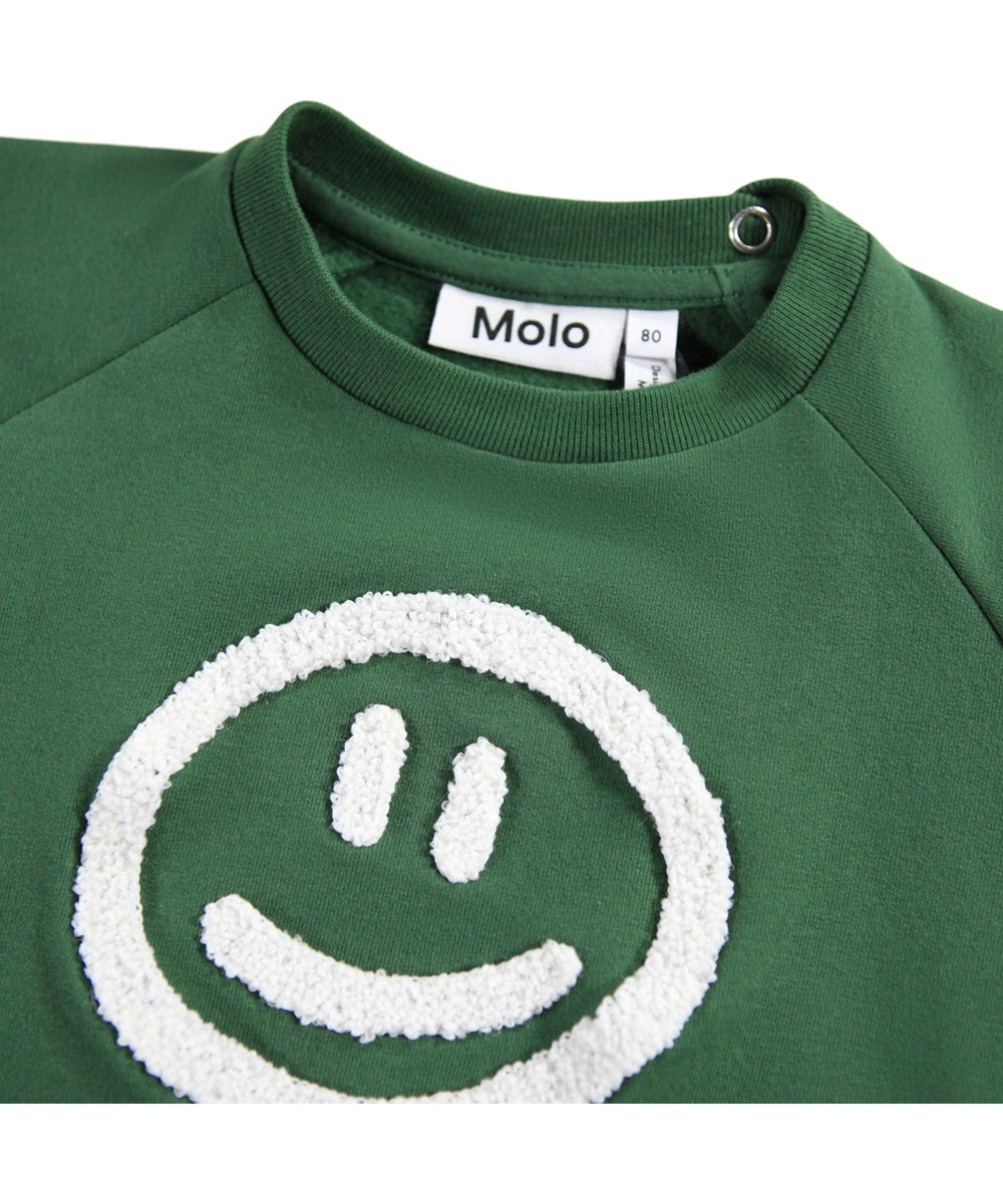 Disc - Pine Tree - Mørkegrøn sweatshirt til de mindste i blødt økologisk bomuld med et broderet smilende ansigt på fronten.