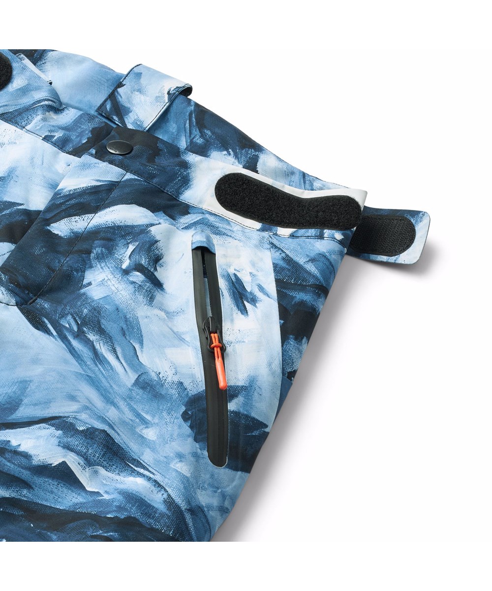 Jump Pro - Arty Mountains - Wind- en waterdichte kinderskibroek met een artistieke print van de Alpen en snowboarders in blauwe en witte tinten. Gemaakt van gerecycled polyester en gevoerd met 3M™ Thinsulate™.