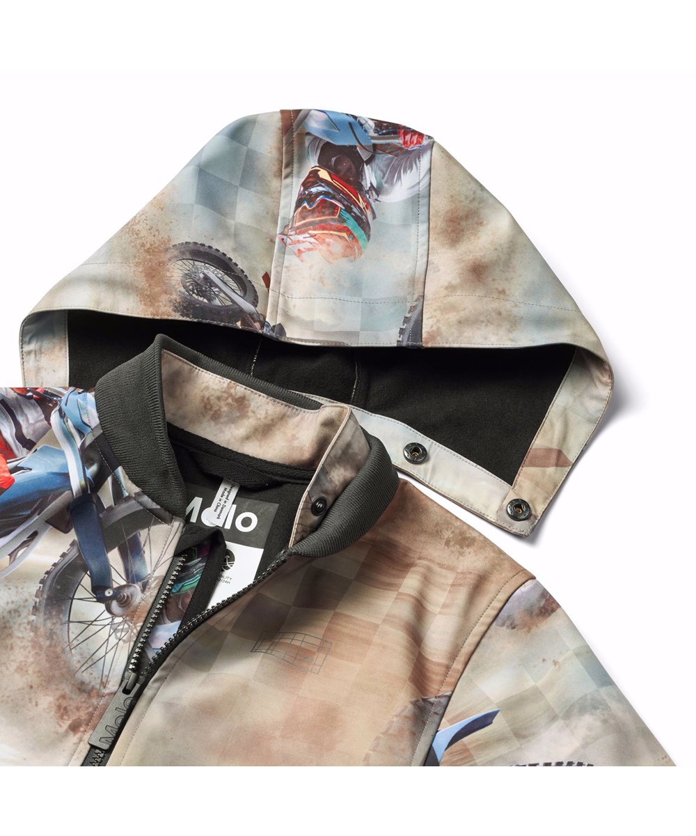 Cloudy - Dusty Cross - Wind- en waterafstotende softshell kinderjas van gercycled polyester met een print van motorcrossers in bruine kleuren.