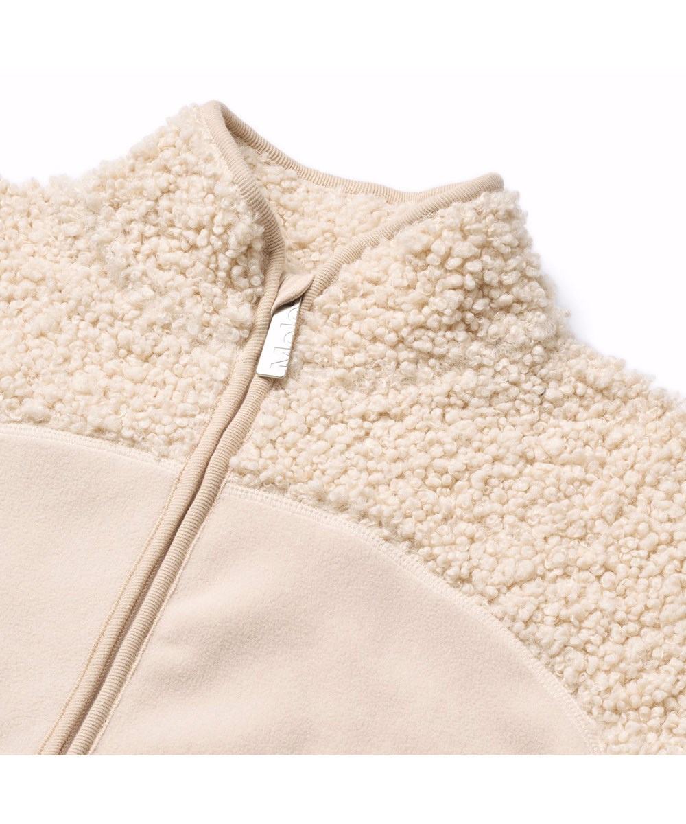 Ulani - Vanilla - Gebroken witte fleecejas voor kinderen gemaakt van gerecycled polyester met bijpassende ribboorden en een voorzak.