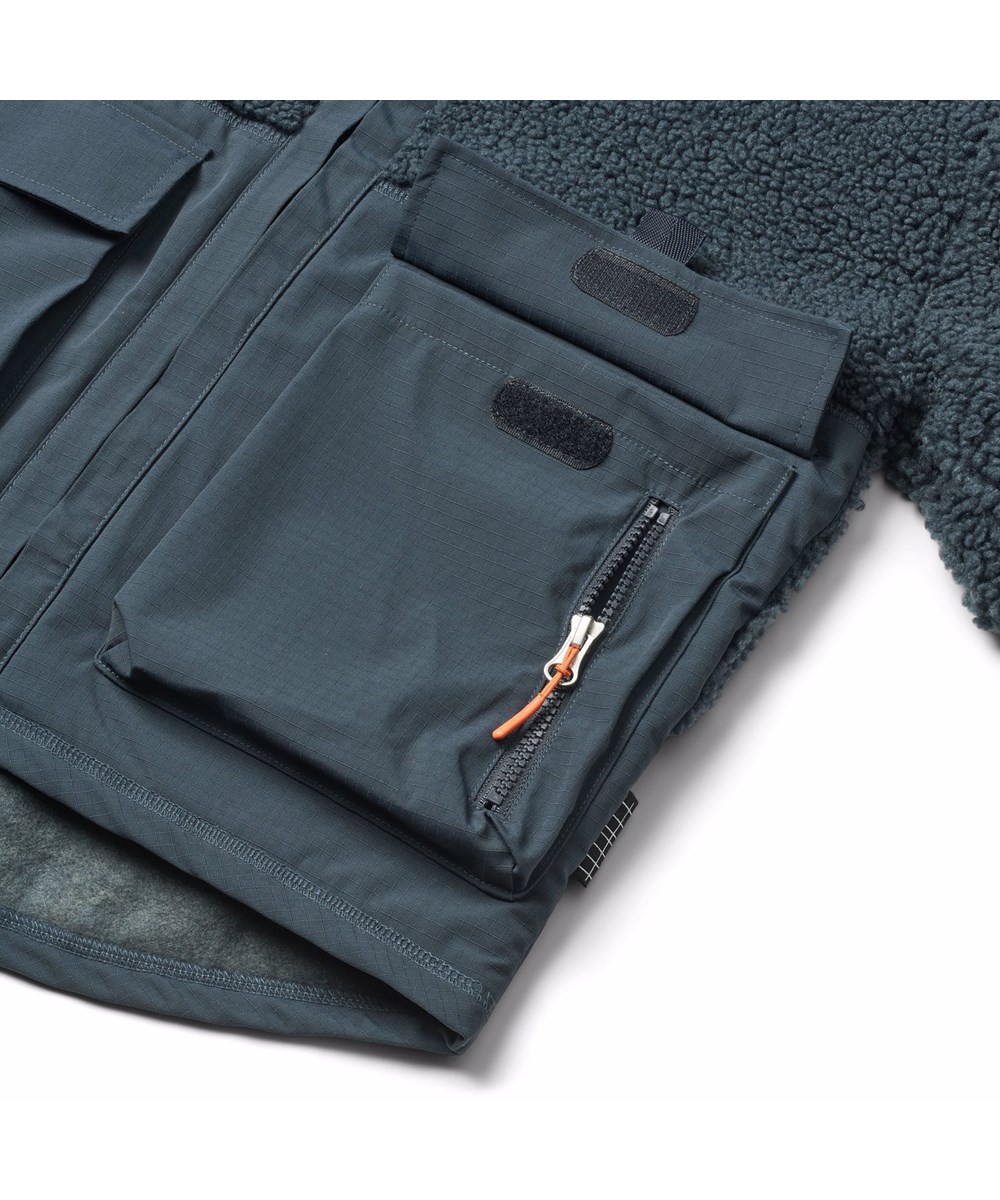 Utha - Night Navy - Donkerblauwe fleecejas voor kinderen gemaakt van gerecycled polyester met details op de mouwen, achterkant en buitenste voorzakken die gemaakt zijn van wind- en waterafstotend duurzaam nylon.