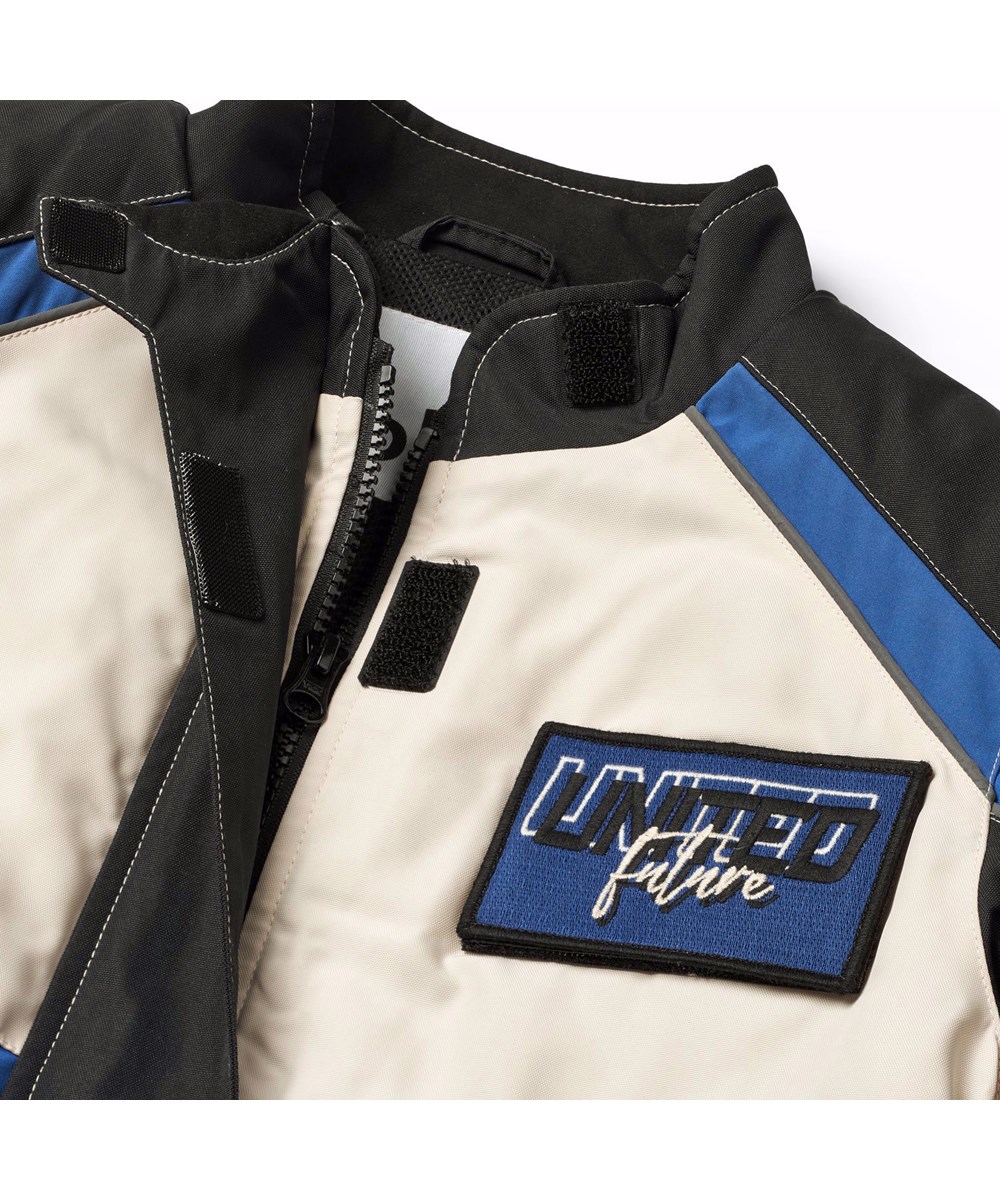 Haddix - Black - Kinderjas  in de kleuren zwart, blauw en gebroken wit en het is geinspireerd op de motorcross wereld met klittenband en patches.