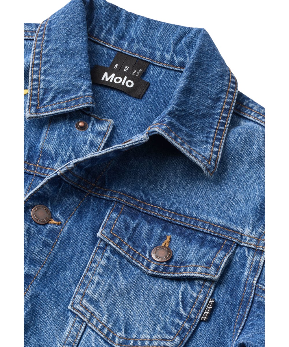 Honore - True Blue - Blauw spijkerjack voor kinderen gemaakt van katoen met kleurrijke geborduurde patches op de achterkant.