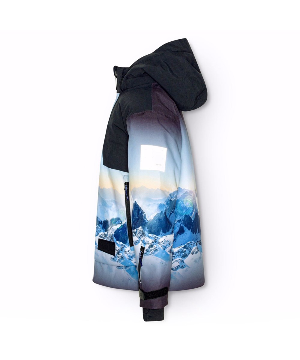 Alpine - High In Sky - Wind- en waterdichte ski-jas voor kinderen van gerecycled polyester met een print van de besneeuwde Alpen met zonnestralen en een heldere lucht.