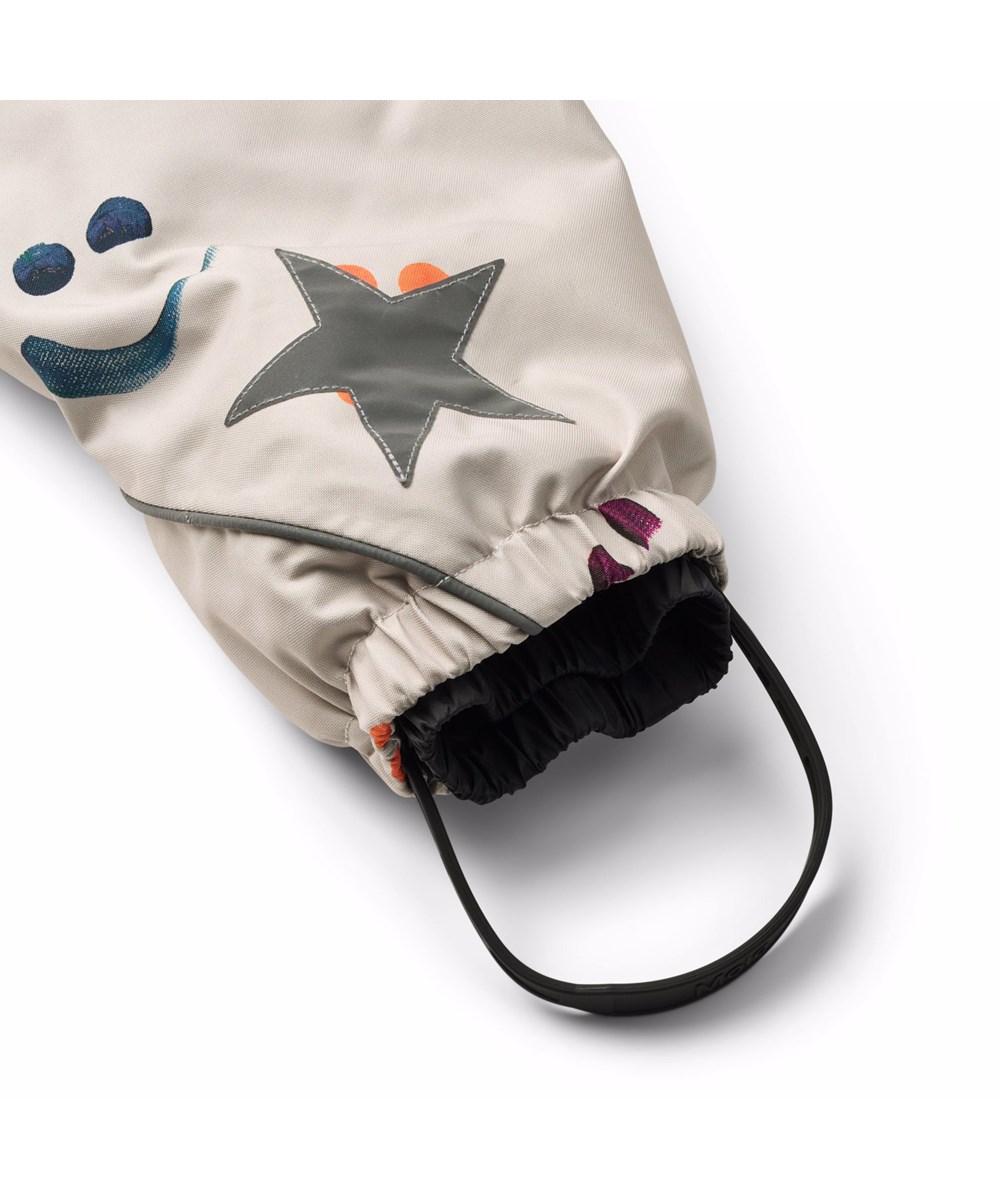 Pyxis Fur - Arty Emotions - Beige wind- en waterdichte skipak voor een koude winter met een print van kleurrijke lachende gezichten gemaakt van gerecycled polyester en gevoerd met 3M™ Thinsulate™.