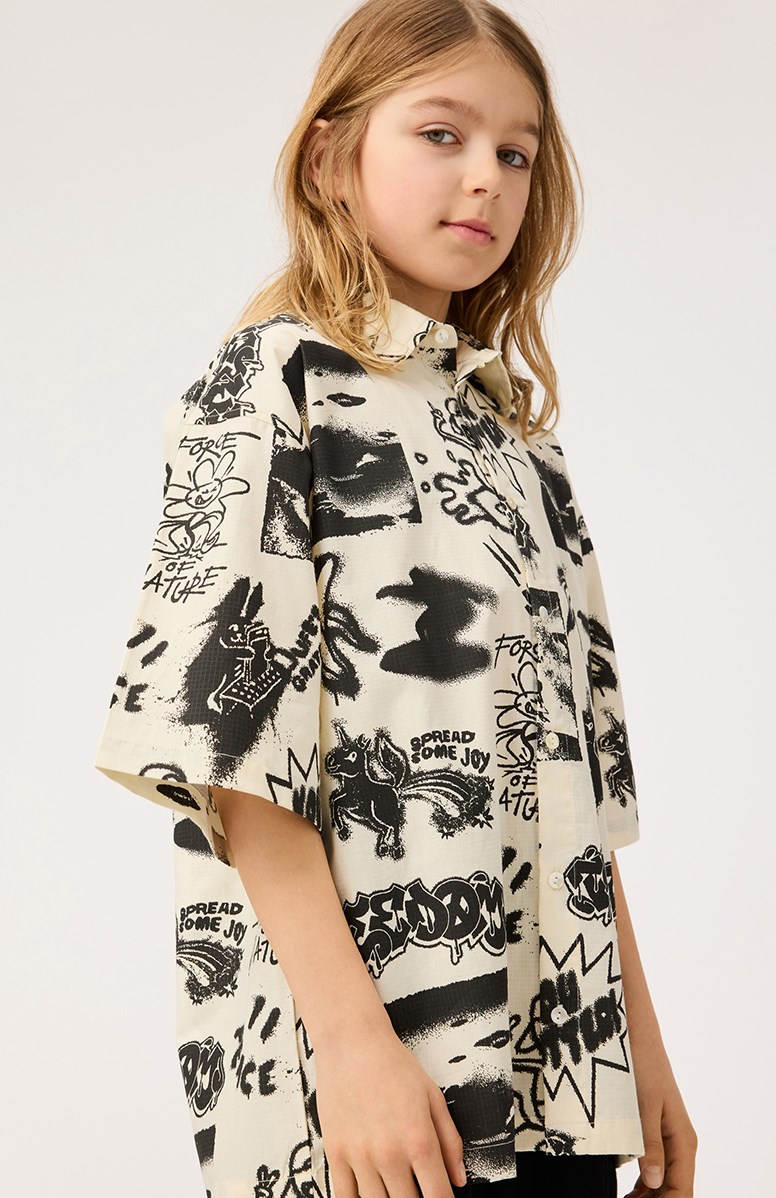 Richie - Art Mix - Beige shirt with print for children in soft organic cotton with wide t-shirt sleeves, classic shirt collar, and button fastening on the front.