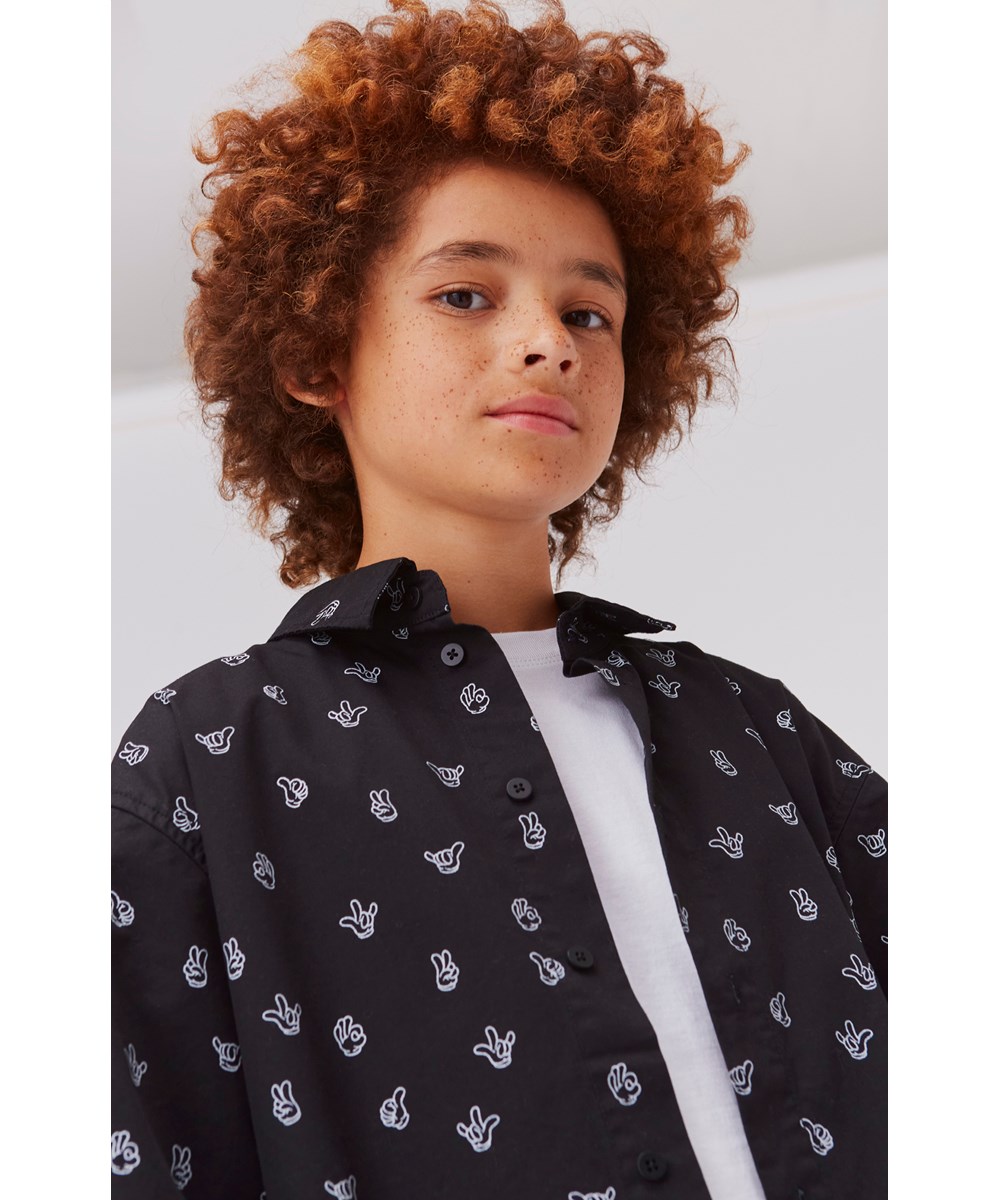 Richie - Friendly Hands - Black short sleeve shirt with a print of hand signs 