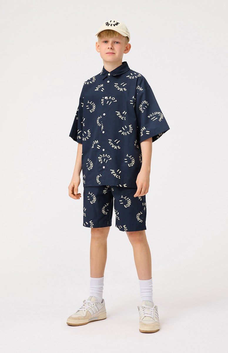 Avart - Smile Words - Knee-length shorts in organic cotton for children. These shorts are blue with smiling faces.