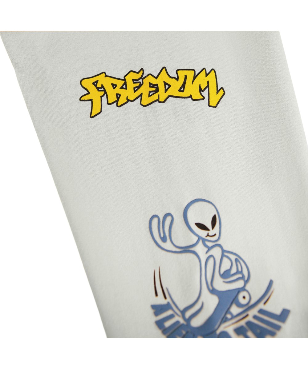 Rube - Comic Skate - Beige, langærmet bluse til børn i økologisk bomuld med ribkant i hals og ærmer med et print af aliens og katte på skateboards samt sjove og søde udsagn ned langs ærmerne.
