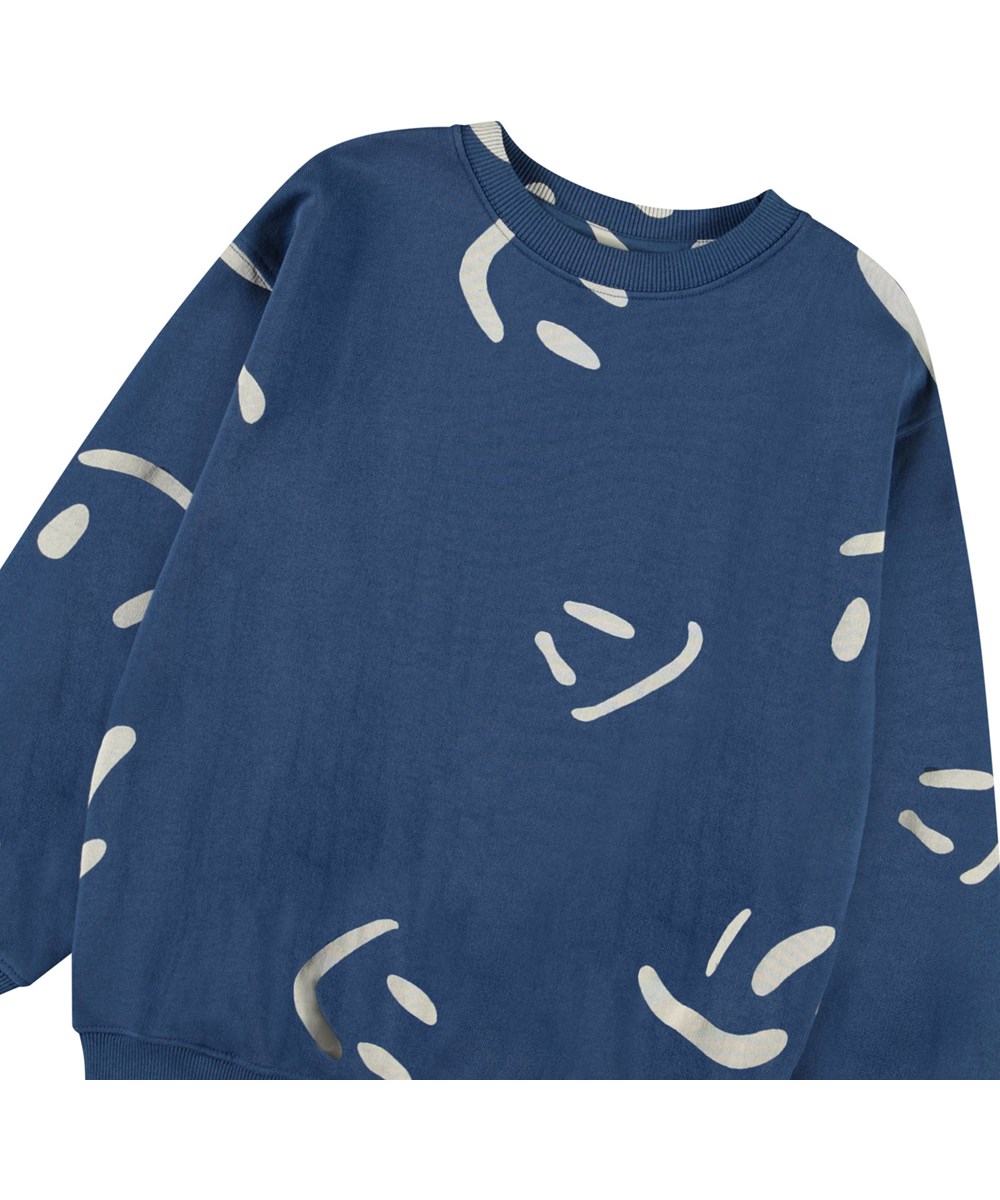 Monti - Big Smiles Blue - Mørkeblå sweatshirt med print til børn i blødt, økologisk bomuld med ribkanter ved hals, ærmer og i bunden af blusen.