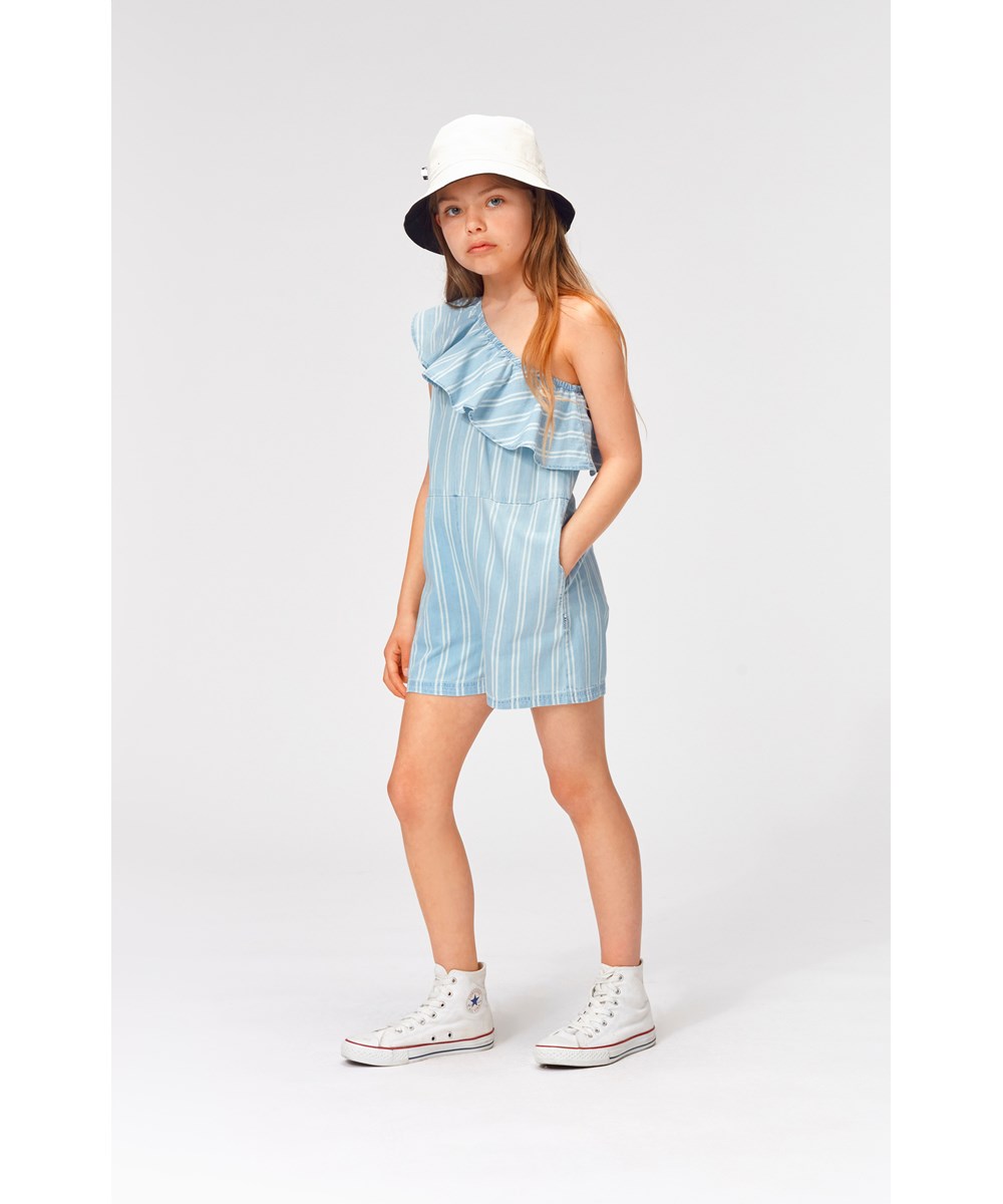 Amira - Striped Chambrey - Ljusblå asymmetrisk byxdräkt med vita ränder.