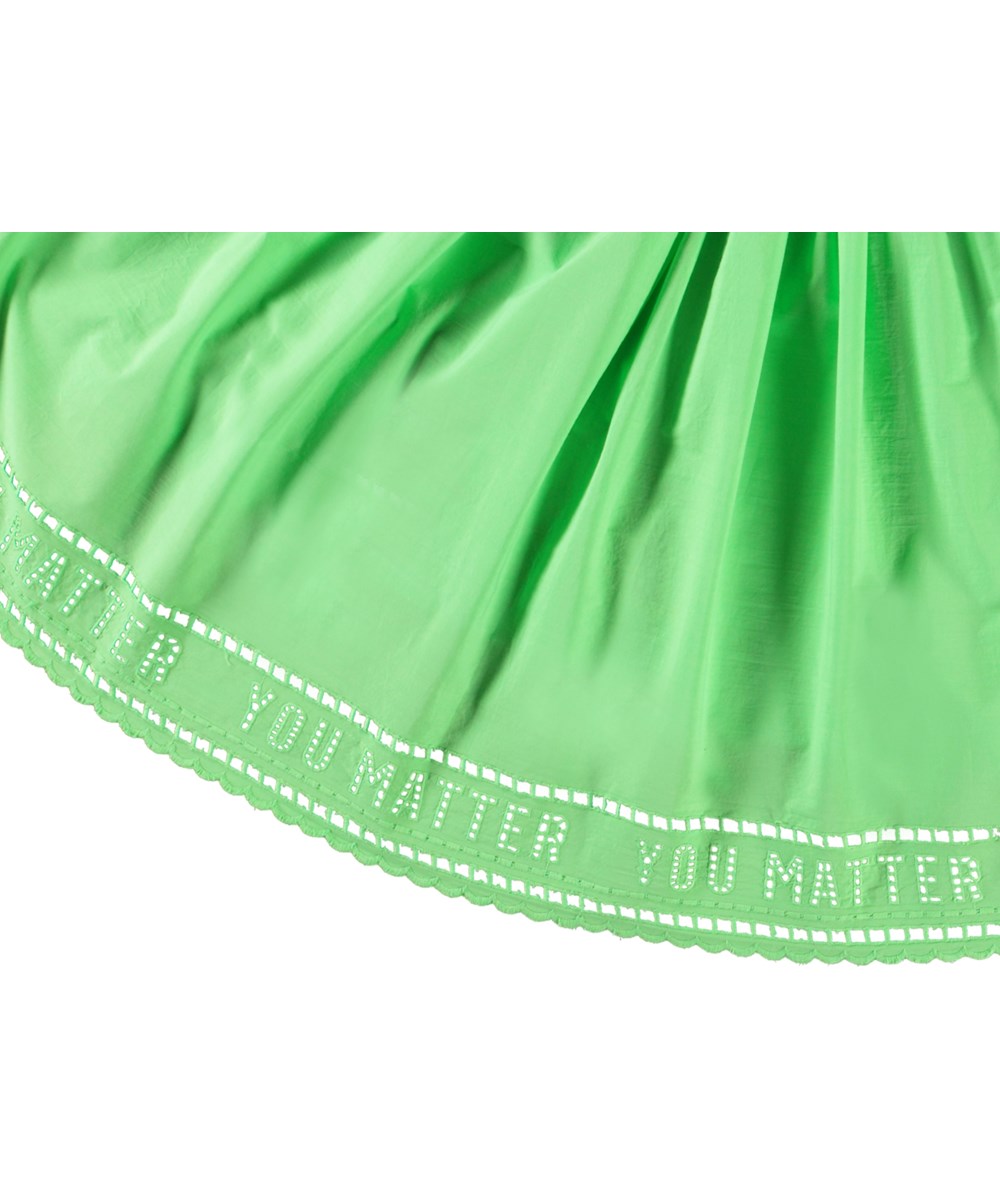 Cibelle - Green Vibes - Långärmad grön klänning för barn i ekologisk bomull med en tät ribbad jerseytopp, rund hals och en volyminös helcirkelskjol i bomullspoplin.