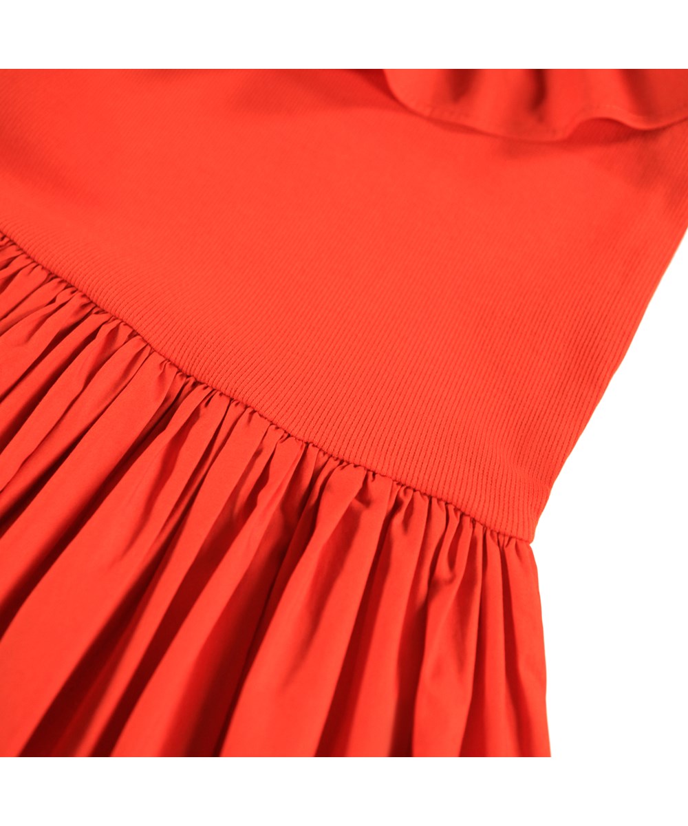 Cille - Rising Sun - Röd knälång klänning för barn gjord av ekologisk bomull med en åtsittande jerseytopp, en volyminös kjol av bomullspoplin och en stor poplinkrage.