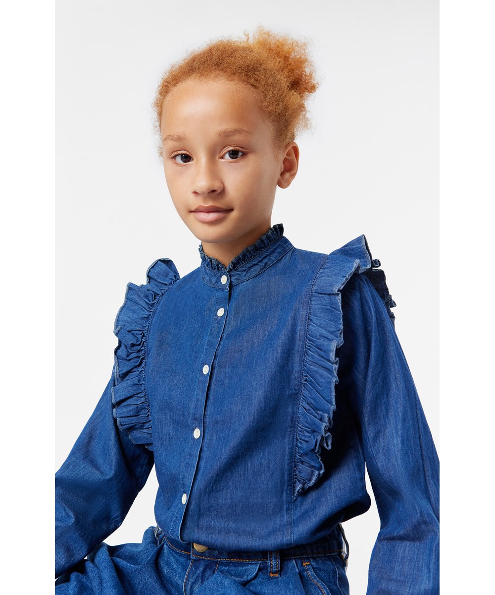 Raphaella - Mid Blue Wash - Lös jeansskjorta i ekologisk bomull med volangdetalj och mandarinkrage.