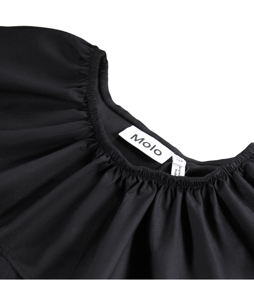 Renate - Black - Svart, åtsittande långärmad topp för barn ti ekologisk bomullsribb med en poplinkrage och elastik som kan bäras off-shoulder eller lyftas upp för att fungera som både krage och ärm.